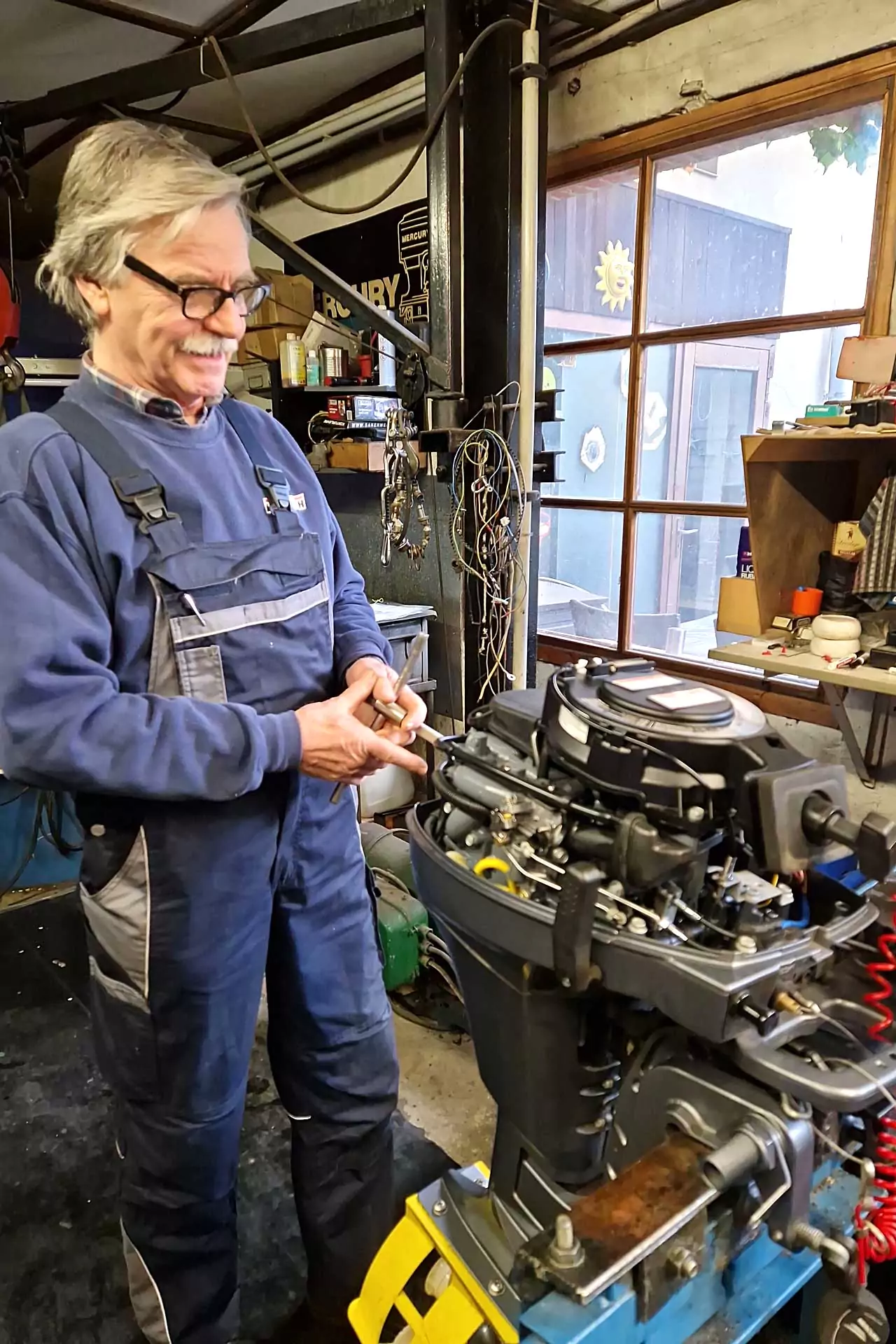 Hartwichs Freizeitmarkt-Service und Verkauf von Zubehör für Boote- Herr Günter Hartwich in Werkstatt bei Reparatur von Bootsmotor